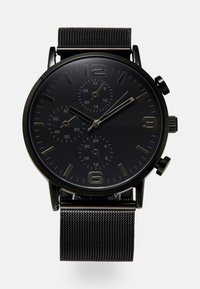 Montre chronographe noire avec un bracelet en maille métallique. Affiche un cadran noir, des index horaires argentés et trois sous-cadrans pour le suivi du temps.