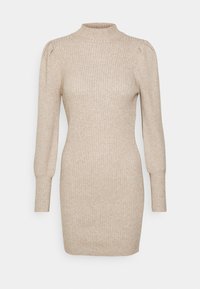 Beige ribbad stickad klänning med hög hals, tajt passform, långa ärmar och subtil puffdetalj vid axlarna. Mjuk textur genom hela plagget.