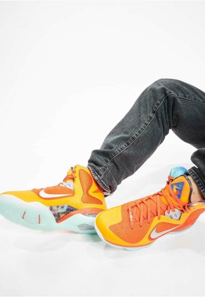 Zapatillas deportivas de color naranja brillante con materiales de malla y sintéticos, que cuentan con un collar acolchado, suela de goma y acentos coloridos en el diseño.
