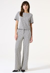 Grijs en wit gemêleerd gebreid topje, gecombineerd met bijpassende wijde broek, met een zachte textuur en korte mouwen. Slank figuur met een ontspannen ontwerp.