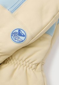 Δερμάτινα γάντια σε κρεμ και ανοιχτό μπλε αποχρώσεις. Διαθέτουν συγκεντρωμένο ραμμάτισμα και στρογγυλή μπλε λογότυπο. Απαλή, λεία υφή.