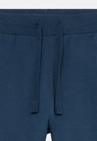 Marineblaue Jogginghosen mit einem gerippten Bund und verstellbarem Kordelzug, glatter Textur und lässiger Passform.