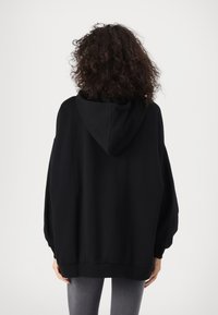 Czarna bluza z kapturem o luźnym kroju, opadających ramionach oraz ściągaczach przy mankietach i u dołu, wykonana z miękkiego materiału o matowym wykończeniu.
