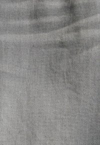 Zbliżenie gładkiego szarego materiału z delikatnym diagonalnym splotem i subtelnymi zmarszczkami.