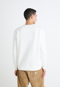 Witte sweatshirt met ronde hals in een soepele textuur, voorzien van een geribde halslijn en manchetten. Gekoppeld aan lichtbruine corduroy-broeken met logo-label.