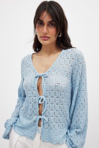 Helle blaue, gestrickte Bluse mit V-Ausschnitt, langen Ärmeln und einer Knoten-Frontschließe. Strukturiertes Muster mit offener Webart-Detaillierung.