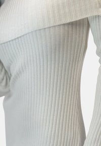 Pull gris clair côtelé avec un design à épaules dénudées. La texture est douce, avec des rayures verticales et une silhouette ajustée.