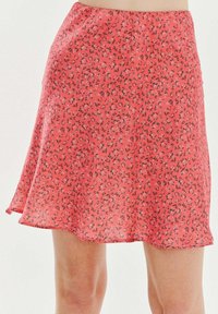 Červená sukně s květinovým vzorem vyrobená z lehké tkaniny, s rozšířeným střihem a lemem, který se jemně vlní, s malými černými detaily.