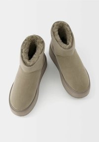 Béžové kotníkové boty vyrobené z semiše, s umělým kožíškem uvnitř, hladkým povrchem, kulatou špičkou a plochou gumovou podrážkou.