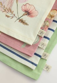 Quatre serviettes en tissu empilées, ornées de motifs floraux en crème et rose, ainsi que de motifs rayés en bleu et vert, avec des étiquettes aux coins.
