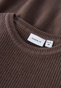 Brun strikket sweater med en tekstureret ribbet design, rund halsudskæring og synlig label med størrelse og mærkeoplysninger.