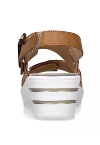 Sandal in pelle marrone con cinturino alla caviglia regolabile e tacco a zeppa bianco con strisce argentate. Texture liscia e design con retro aperto.