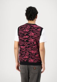 Gebreide sweatervest in het zwart met een roze abstract patroon, voorzien van een geribde kraag en zoom. Draag het over een wit T-shirt voor een casual look.