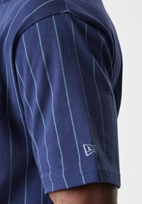 Mørkeblåstripet kortermet skjorte med vertikale teal-striper og en liten brodert logo på ermet. Glatt bomullsmateriale.