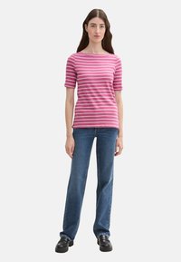 Striped pink T-shirt with a boat neckline and short sleeves, paired with straight-leg blue jeans and black chunky shoes.