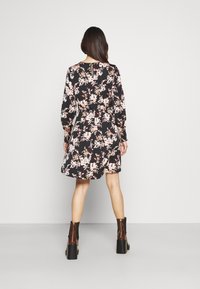 Floral dress with long sleeves, black base, pink and white flowers, fitted waist, knee-length, paired with brown platform boots.