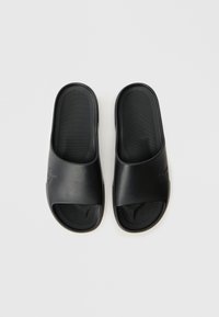 Black slide sandals made of smooth plastic. Features a wide strap and textured insole. Open-toe design with a minimalist look.