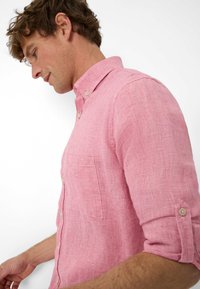 Camicia a quadri rossa con maniche lunghe, taschino sul petto e maniche arrotolate. Tessuto leggero con una finitura testurizzata.