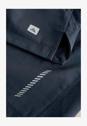 Pantaloni sportivi di un blu navy scuro con una texture liscia, bordi cuciti, una toppa con logo e righe diagonali riflettenti per una maggiore visibilità.
