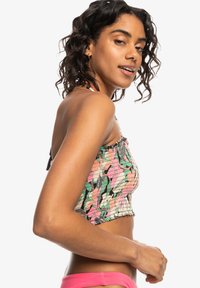 Kleurvolle cropped top met smockstructuur, voorzien van een mix van roze, groen en zwarte patronen. Halterneck ontwerp met verstelbare bandjes.