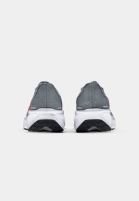 Gray running shoes with mesh upper, padded collar, and white midsole. Notable red accents and textured black outsole for traction.