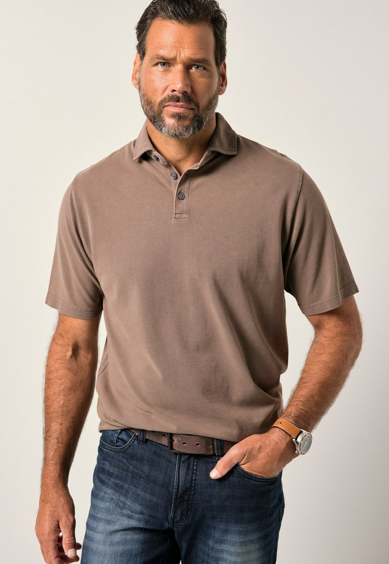 Hnědá polo tričko s krátkým rukávem, s límečkem, knoflíkovou légou a texturovanou tkaninou, v kombinaci s tmavými džínami a hnědým koženým opaskem.