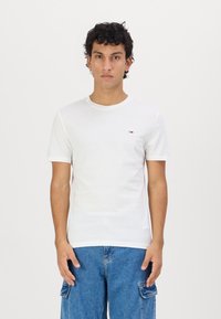 Tricou alb cu mânecă scurtă, din bumbac, cu decolteu rotund și un mic logo pe piept. Asortat cu pantaloni scurți cargo din denim albastru.