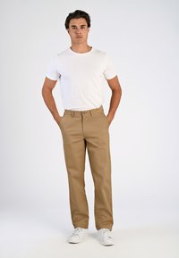 Beige katoenen chino's met een rechte pijp, voorzien van een knoopsluiting en zijzakken, gecombineerd met een wit T-shirt met korte mouwen.
