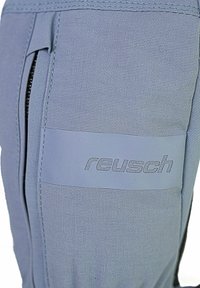 Helle blaue Stoffhandschuhe mit strukturierter Oberfläche, ausgestattet mit einer Reißverschlusstasche und einem sichtbaren "reusch"-Logo in einem dunkleren Farbton.