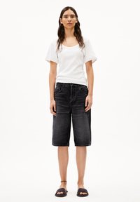 Witte ribbelige top met korte mouwen gecombineerd met zwarte denim bermuda shorts. De shorts hebben een ontspannen pasvorm en een standaard vijf-pocket ontwerp.