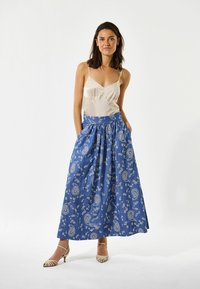 Mėlynas paisley rašto sijonas su kišenėmis, pagamintas iš minkštos medžiagos, derinamas su smėlio spalvos maikute. Sijonas turi elastinę juosmenį ir klosčius.