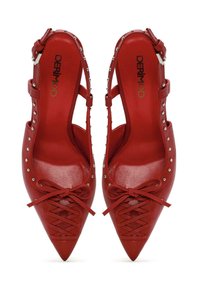 Scarpe rosse in pelle con punta affusolata, design a ritaglio, lacci sul davanti e dettagli in borchie lungo i lati. Presentano una texture raffinata e lucida.