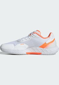 Λευκό αθλητικό παπούτσι με επάνω μέρος από διχτυωτό ύφασμα, πορτοκαλί λεπτομέρειες και υφή στη σόλα. Διαθέτει επενδεδυμένο λαιμό και ενισχυμένη μύτη για αντοχή.