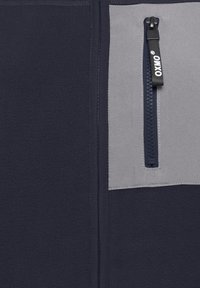 Navy fleece fabric with a contrasting light gray zippered pocket. Features a black zipper pull with "OXIXO" branding. Textured finish.