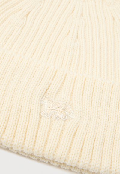 Κρέμα πλεκτό σκουφάκι με ριγωτή υφή, που διαθέτει ένα μικρό κεντητό σχέδιο αλεπούς στο μπροστινό μέρος. Μαλακό, ζεστό υλικό.