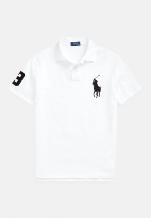 Polo blanco de algodón, con un logo bordado en negro de un jugador de polo y un número "3" en negro en la manga izquierda. Diseño clásico de cuello.