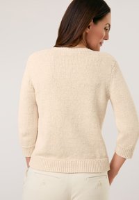 Beige gestrickter Pullover mit Dreiviertelärmeln, geripptem Saum und Bündchen, mit strukturierter Oberfläche und lässigem Schnitt.