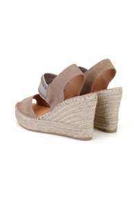 Wedge sandalen met een beige suede bovenkant, elastische band en geweven jute hak. Open teen ontwerp met uitsparingen aan de zijkanten.