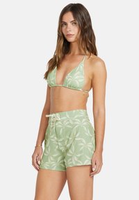 Zeleni bikini top s triangularnimi skodelicami in nastavljivimi naramnicami, v kombinaciji z ujemajočimi zelenimi hlačkami, ki imajo vzorec palmovih listov in vrvico za zategovanje.