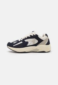 Marineblå og kremfarget sneakers laget av mesh og semsket lær, med en kraftig såle, teksturerte detaljer og kontrasterende fargedetaljer.