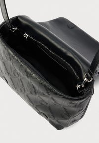 Fekete bőrből készült kézitáska dombornyomott geometriai mintákkal, cipzáras záródással és egyetlen vállpánttal; a bélés sötét, nincs benne további zseb.