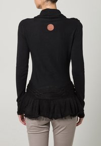 Schwarzer Cardigan mit einem taillierten Oberteil und mehrlagigem, gerafftem Saum. Er zeichnet sich durch einen strukturierten Saum und ein rundes, geprägtes Logo auf der Rückseite aus.