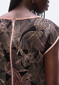 Must lillemustriga kleit, millel on roosa joonistusmustritega must taust ja seljaosas tõmblukk. Sile kangas, lühikeste varrukatega ja ümar kaelus.