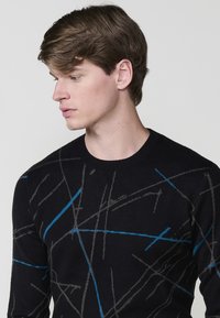 Suéter negro con cuello redondo, que presenta un patrón de líneas abstractas en azul y gris sobre una textura suave. Diseño de corte clásico.
