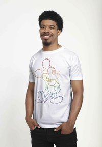 Hvid bomulds-T-shirt med en flerfarvet omrids af en tegneseriefigur. Korte ærmer, rund halsudskæring, afslappet pasform.