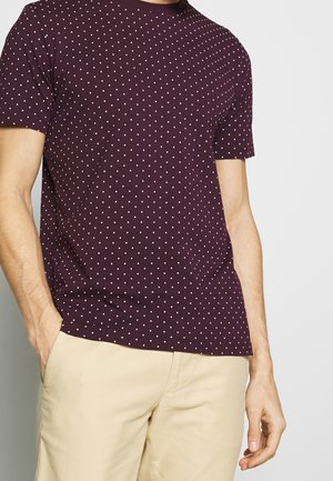 Maroon short-sleeve T-shirt featuring a polka dot pattern in white, made from soft fabric, with a round neckline and relaxed fit.