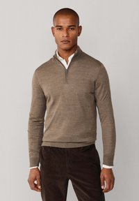 Bruine, lichtgewicht zip-neksweater met geribde manchetten en zoom, gedragen over een witte overhemd met kraag. Soepele textuur, slim fit.