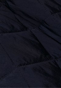 Tela acolchada azul marino con textura suave y brillo, con patrones de costura angulares y un diseño ligero.