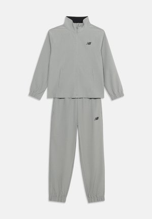 Chándal gris claro de New Balance con chaqueta con cremallera que incluye bolsillos laterales y puños elásticos, pantalones a juego con puños elásticos y logo.