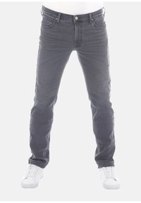 Jeans de mezclilla gris con corte ajustado, estilo de cinco bolsillos y detalles de desgastado ligero. Combinados con zapatillas blancas. Parte delantera plana y diseño clásico.